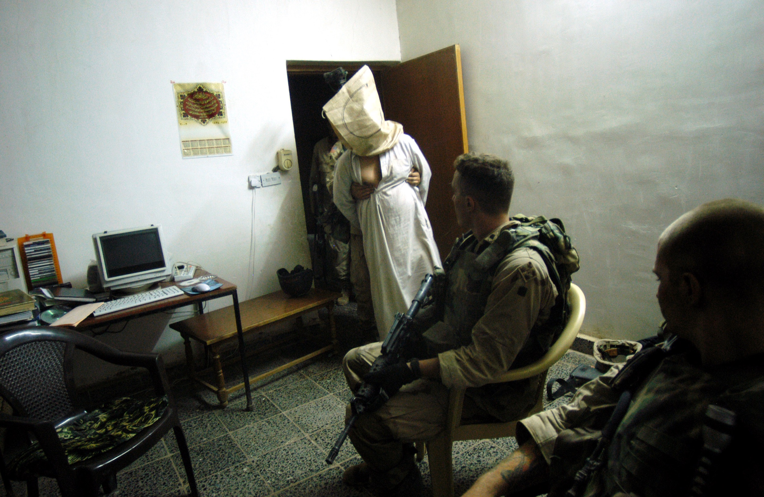 US soldiers stand over detained Iraqis, believed to be supporters of former Iraqi leader Saddam Hussein, 30km north of Baghdad, June 2003.