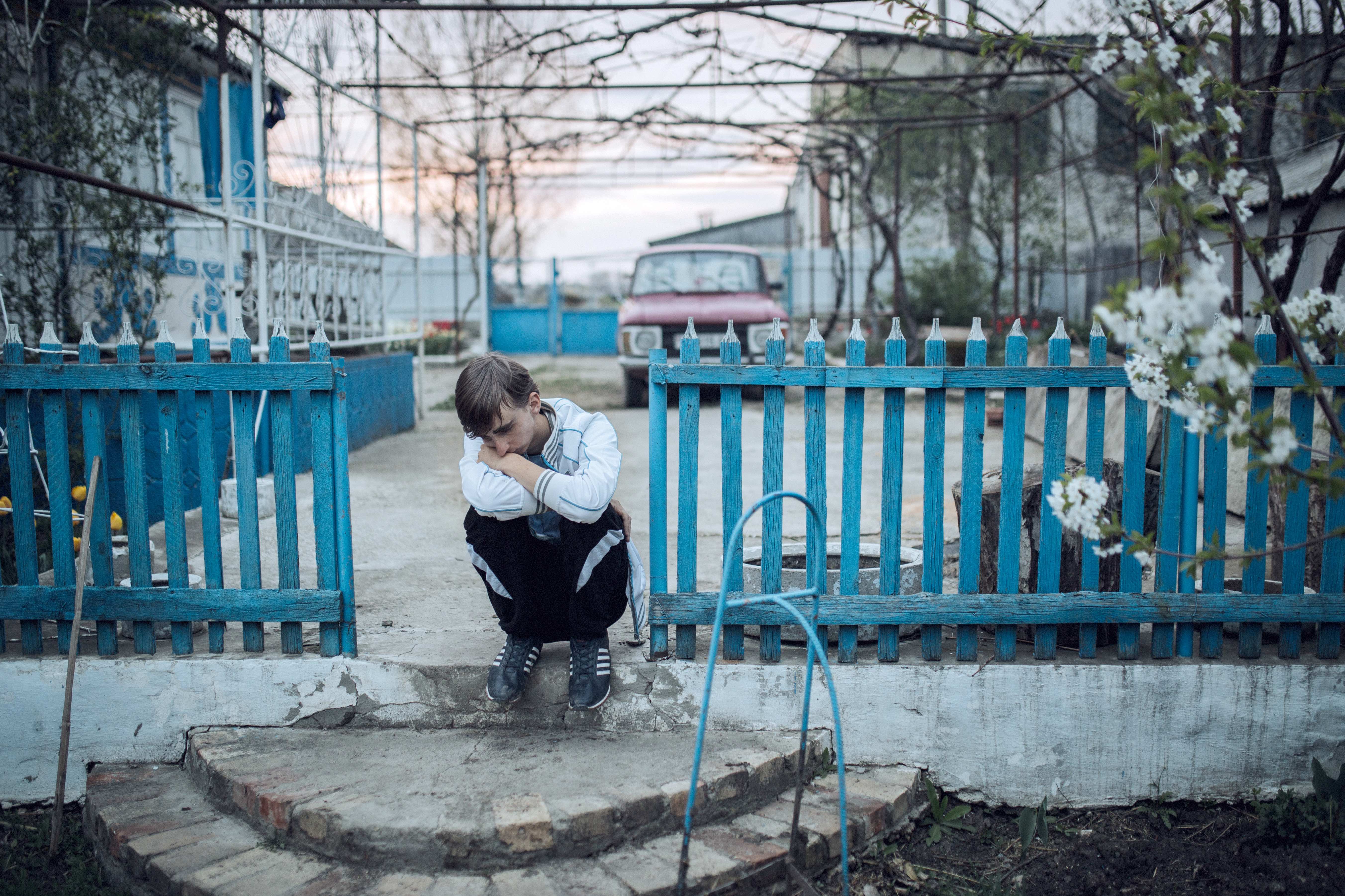 Vasya sits on the porch of his parents' house in Rotar. Since leaving school, he has worked as a watchman for a dilapidated factory and helped his sister make pizzas at a restaurant in Kiev. Now he and his mother work full-time on the farm. Despite few other prospects, Vasya never complains about life in the village and openly admires its beautiful scenery.