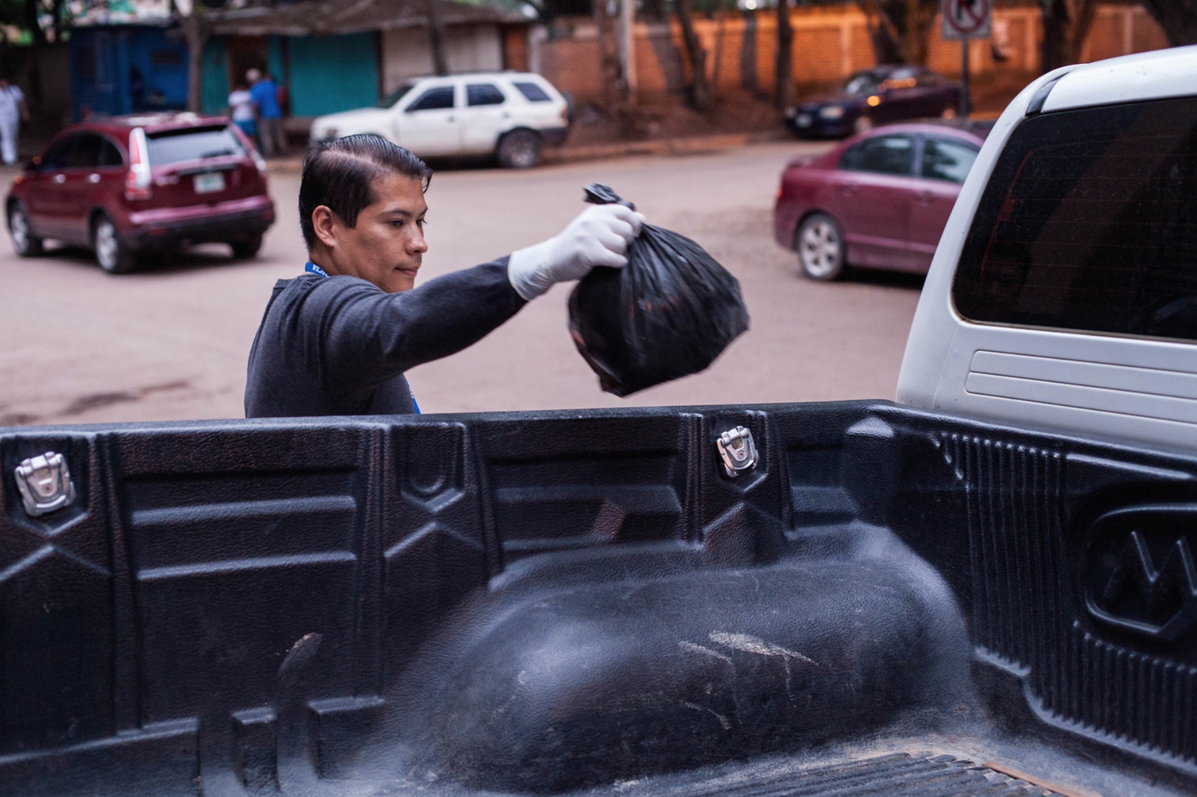 A worker at the Forensics Morgue in Tegucigalpa picks up a decapitated head from the back of a pickup truck. 7th August 2017.