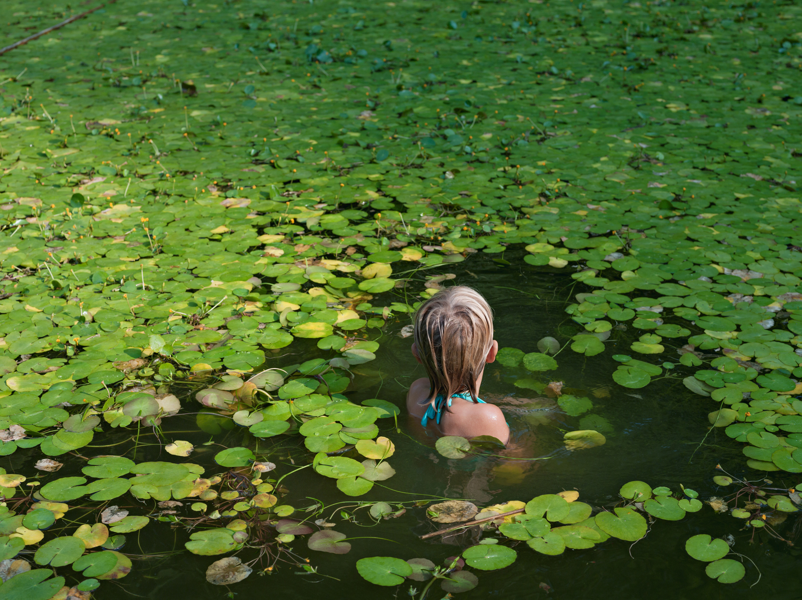 Maddie with invasive water lilies, North Carolina. © Lucas Foglia, courtesy of Michael Hoppen Gallery, London.