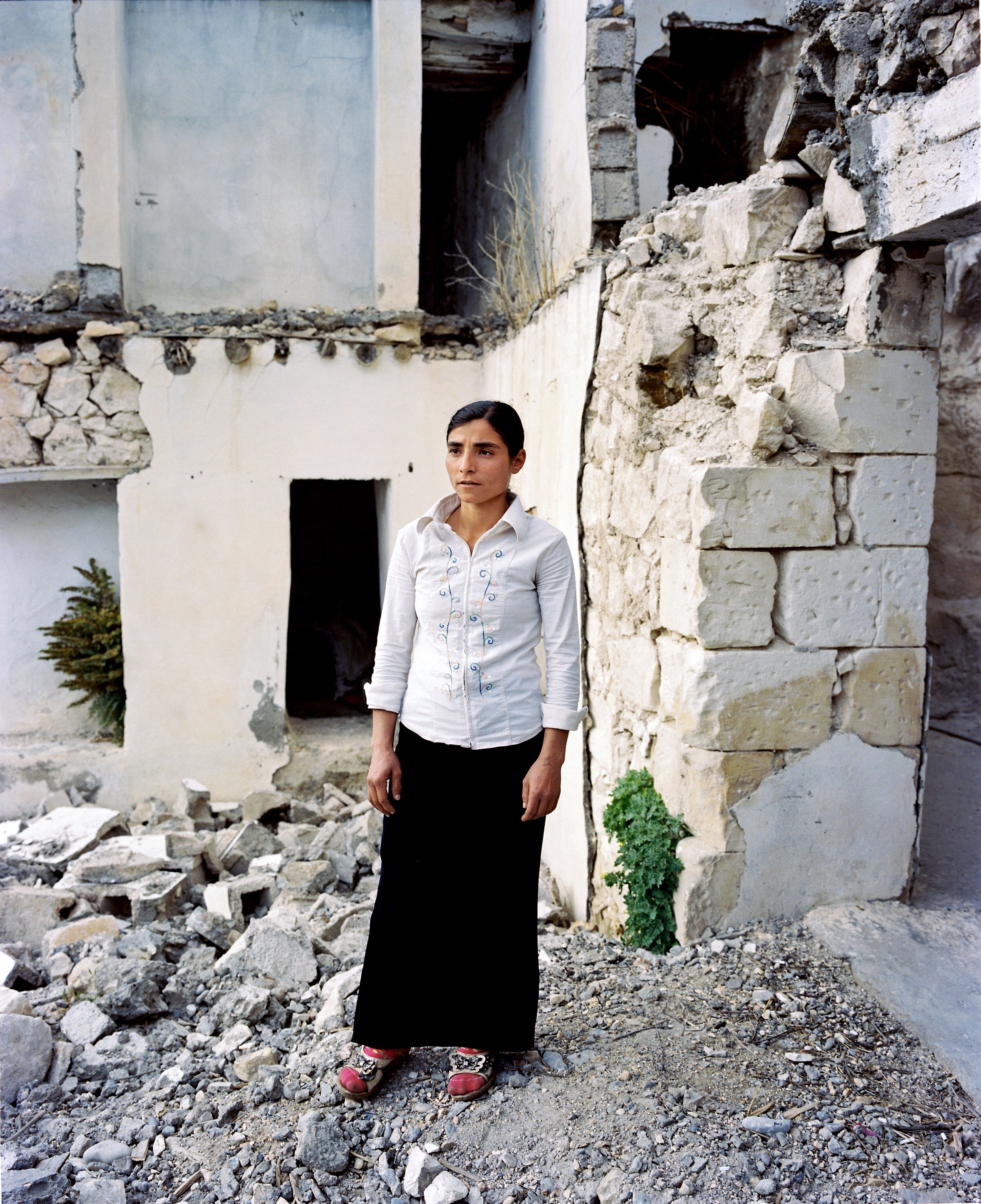 A woman stands in the ruins of the flooded village of Savaçan, facing the reservoir lake of the Birecik Dam on the Euphrates River.