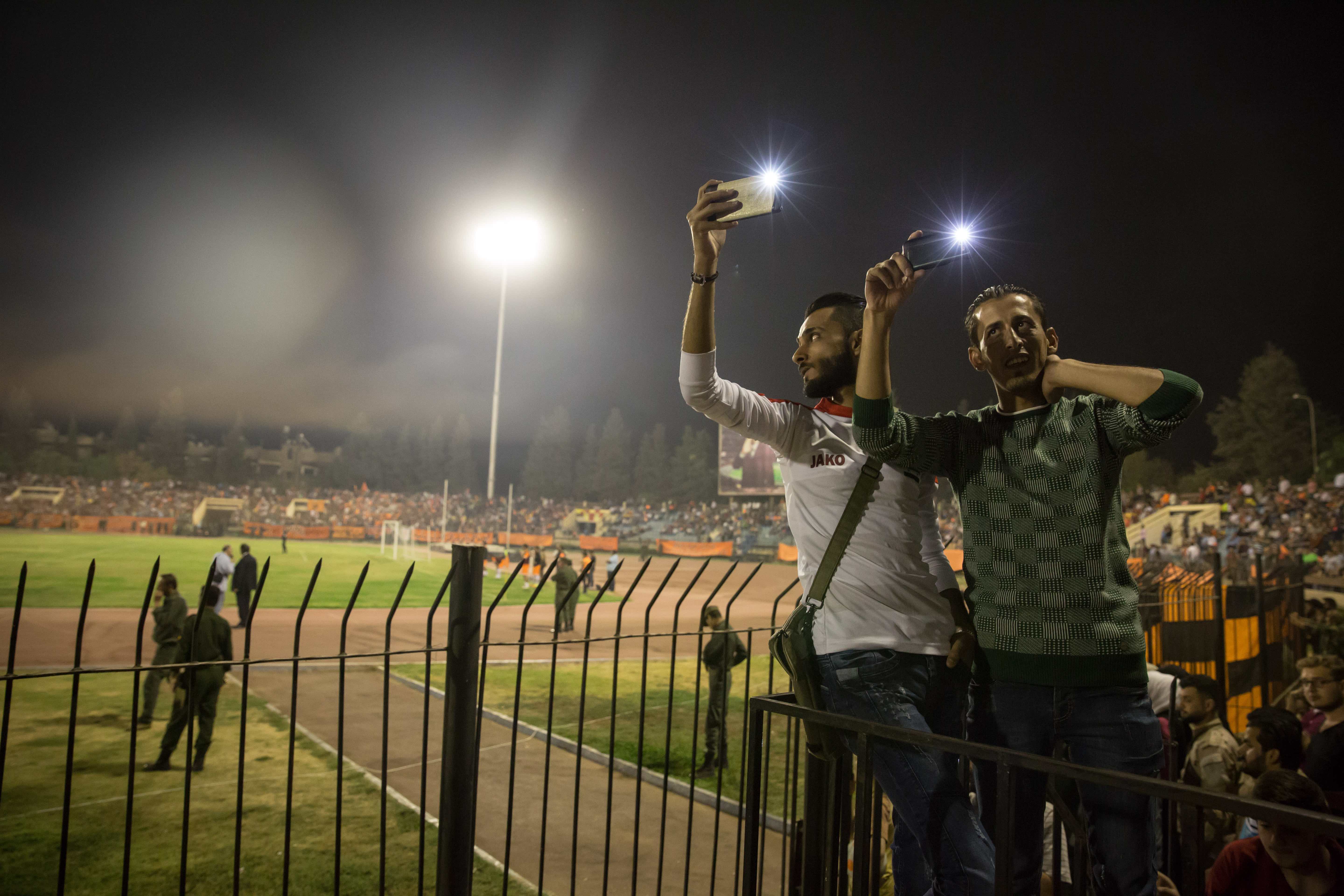Two men film the fans in the stalls. For years, crowds this size wouldn't have gathered together because the security risk was too high.