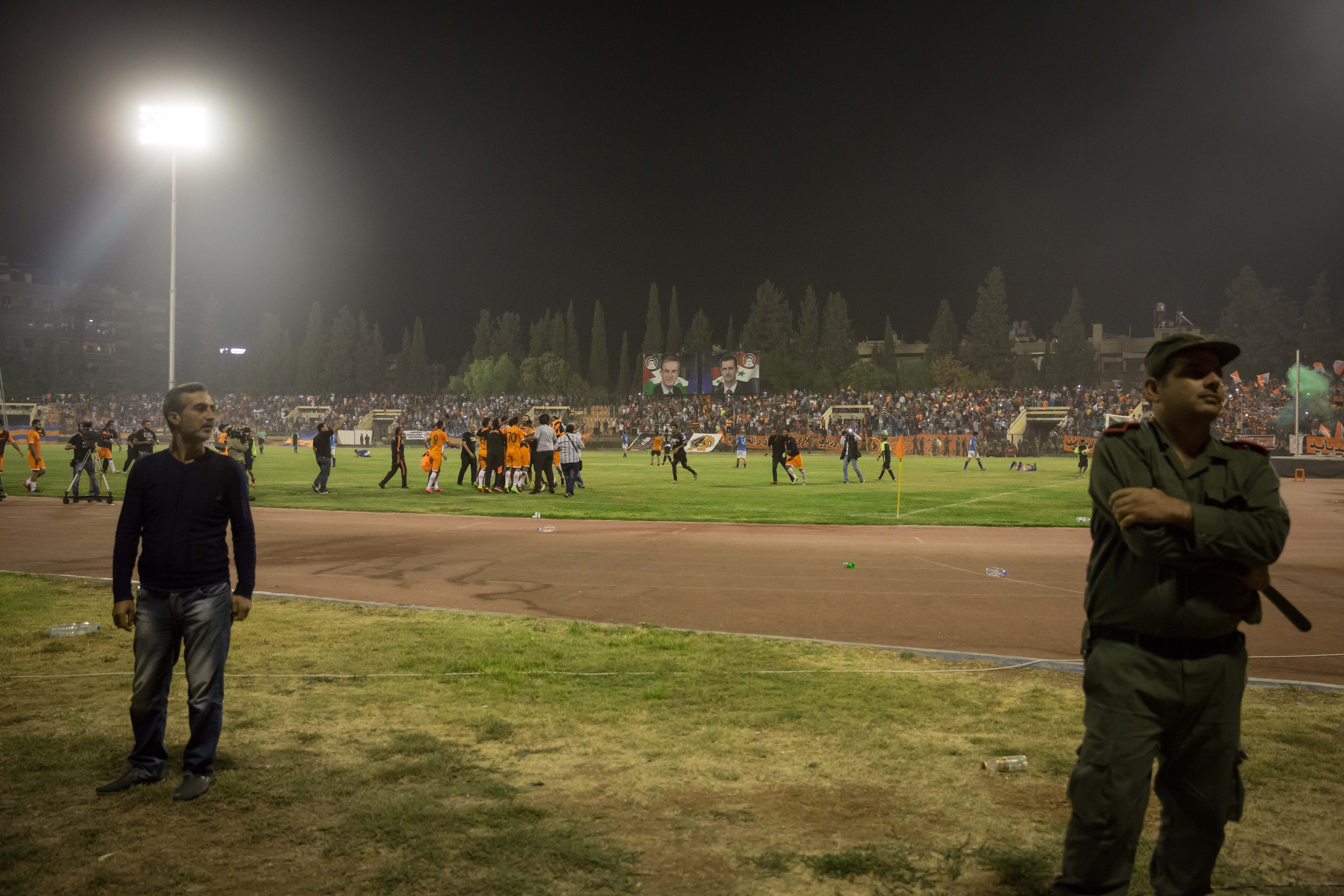 Soldiers stand guard as Al-Wahda from Damascus celebrate their victory in the background.