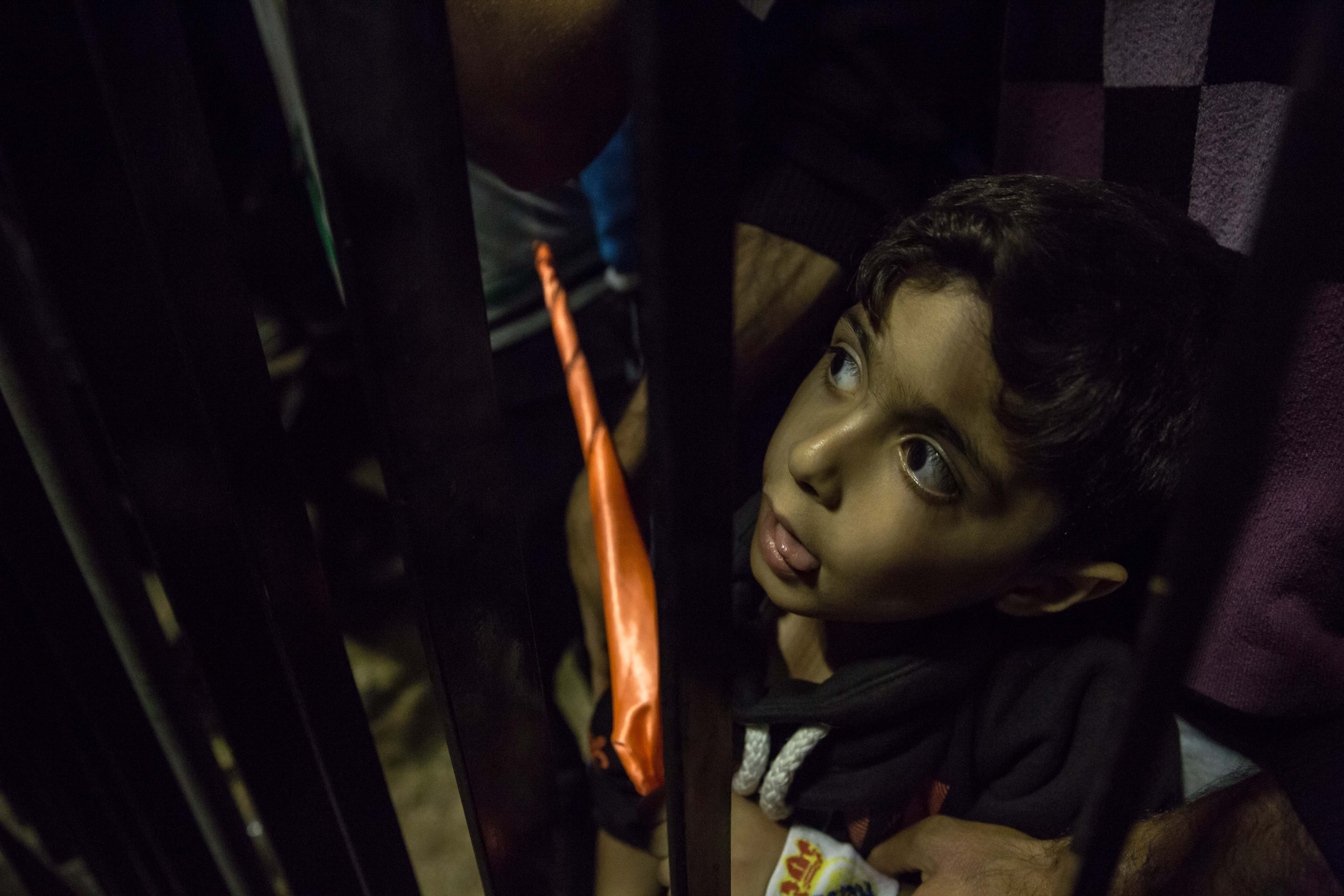 A boy gazes through bars at the game in Tishreen Stadium.