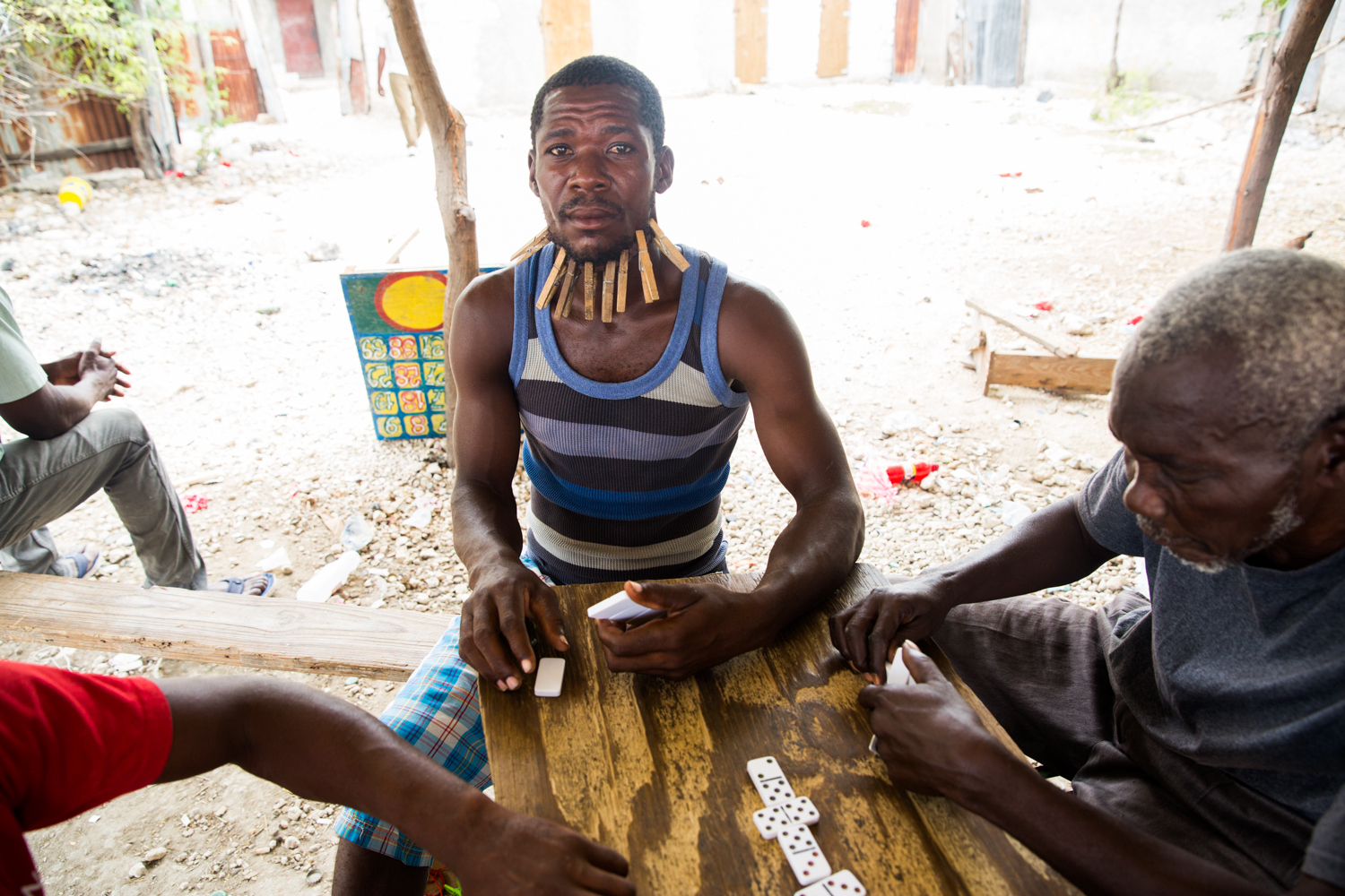 A man plays bourik in Croix-des- Bouquets. Bourik is Haitian dominos. If you lose, you put a close pin on your face.