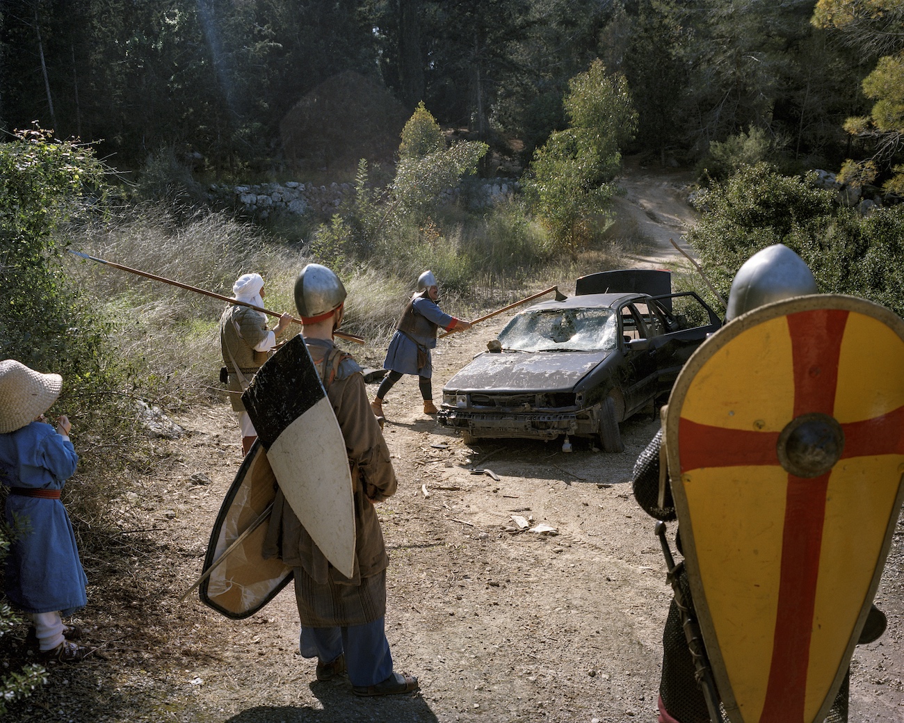 February 24, 2017. Peru Forest near Latrun, Israel. As a little joke, an Israeli reenactment group departs from the historical protocol and slams away at a car wreck. The historical era they are devoted to is that of the crusades. At the Council of Clermont on November 27, 1095, Pope Urban II invoked the Christians to crusade in the Holy Land. They should drive away the Muslims living there and seize the holy sites in Jerusalem for the Christians.