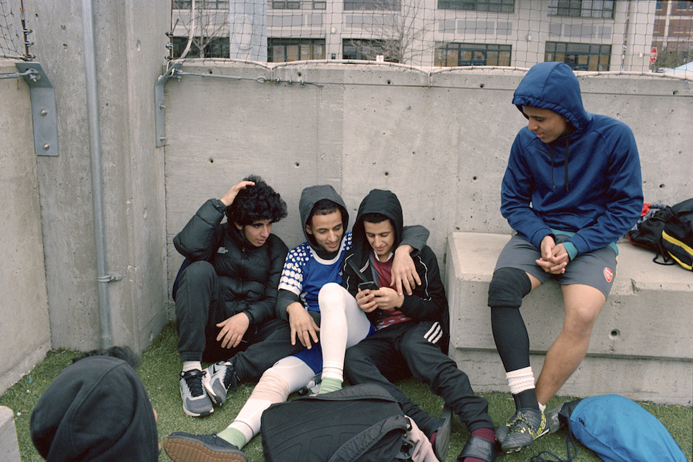 Young members of the Yemen United Soccer team watch snapchat videos on their phones after an early morning practice in Brooklyn, New York.