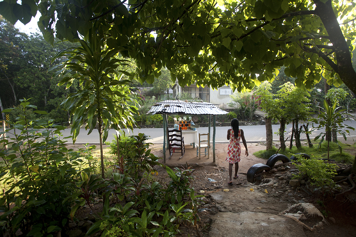 Loma de Cabrera, Dajabón – Nov. 9, 2014: Elena Julienne walks from her house to her stand to sell artisan products, including milk fudge, toasted cashew nuts, and coconut sweets. Originally from Haiti, Julienne is married to a Dominican man and has been selling sweets by this road for 14 years. © Tatiana Fernandez